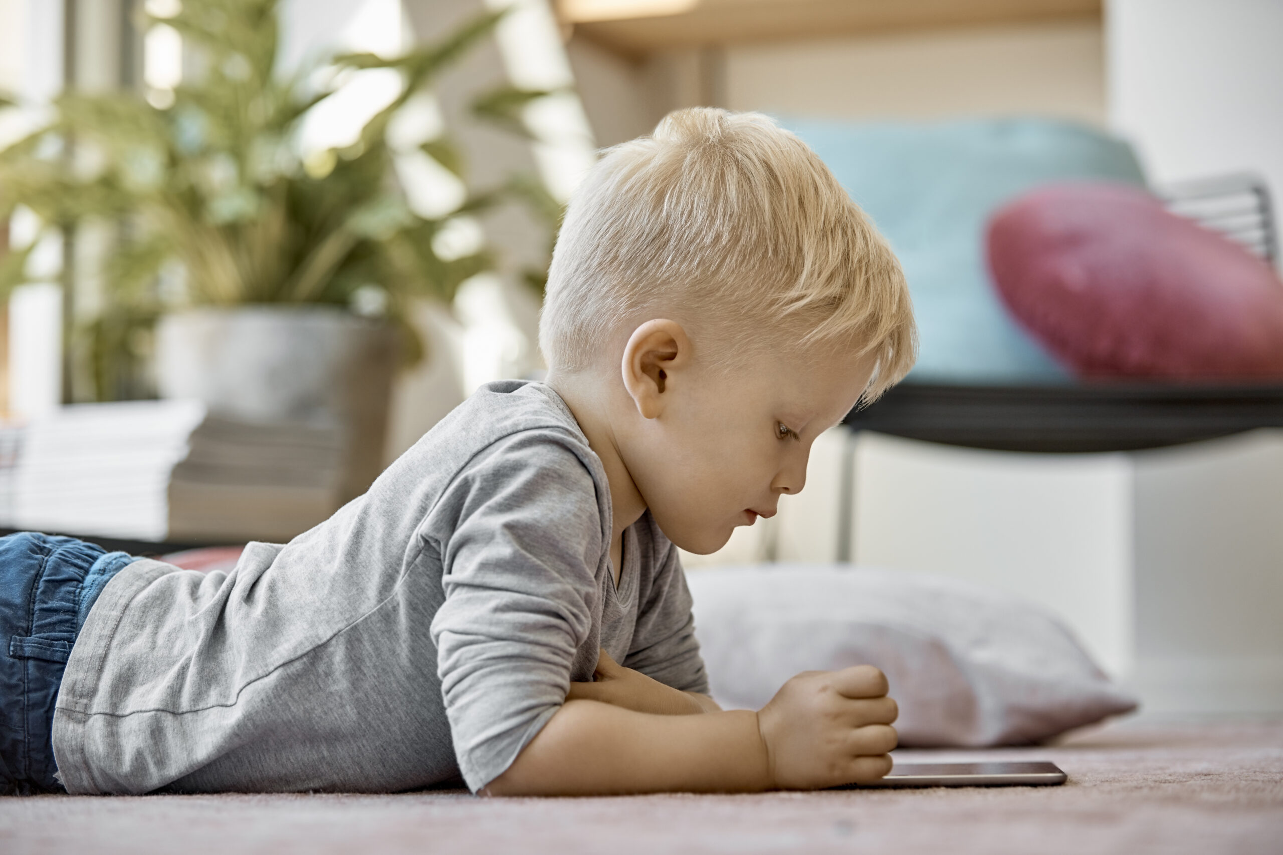 Lille dreng ligger på gulvet med en iPad